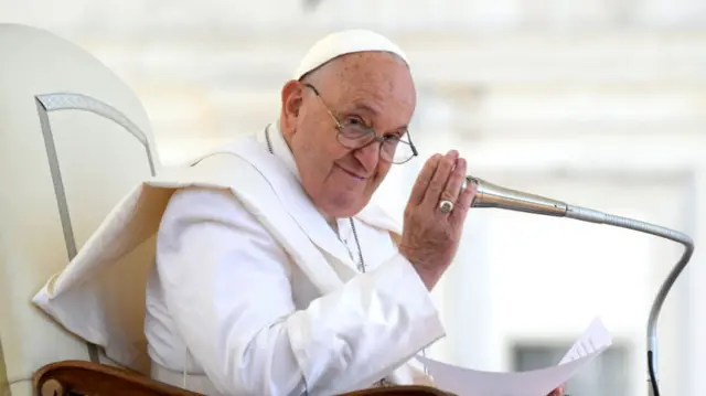 Pope Francis smiling while holding microphone