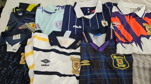 Seven retro Scottish football kits sit neatly folded on a bed