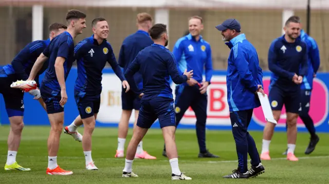 Scotland manager Steve Clarke smiling with his players while they warm up during a training session at Euro 2024