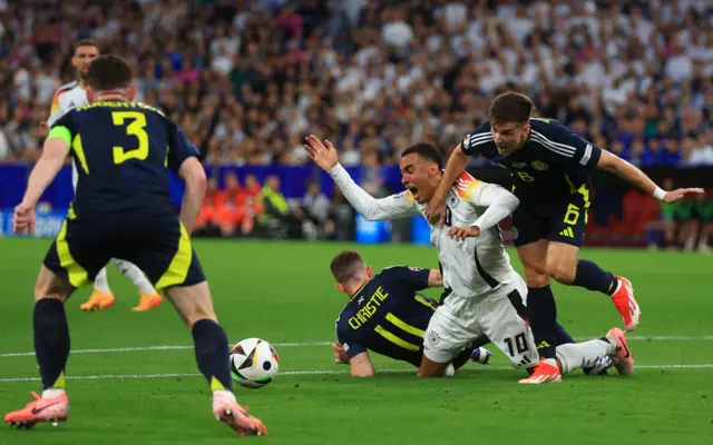 Jamal Musiala (C) of Germany is fouled during the UEFA EURO 2024 group A match between Germany and Scotland in Munich