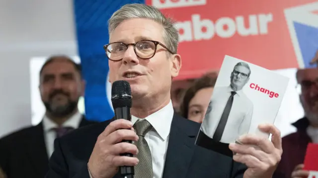 Keir Starmer holds up his manifesto