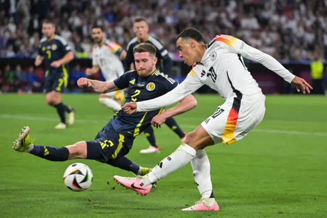 Jamal Musiala (R) shoots but fails to score past Scotland's defender #02 Anthony Ralston (L) during the UEFA Euro 2024 Group A football match between Germany and Scotland at the Munich Football Arena in Munich