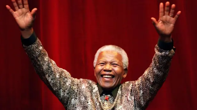 Nelson Mandela smiling with arms raised