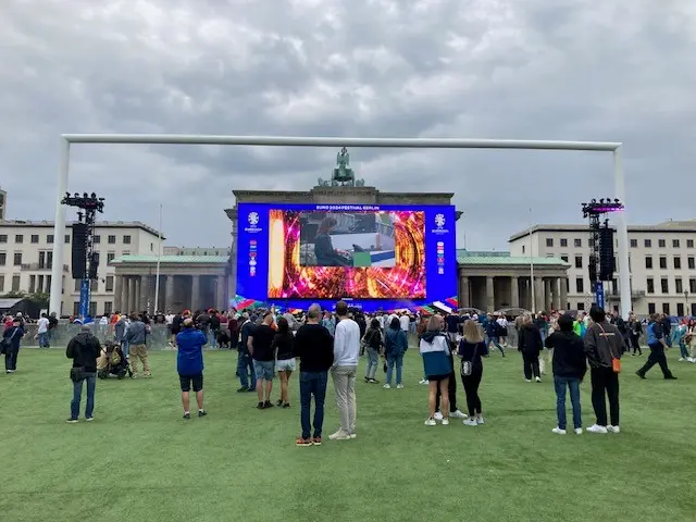 A big screen in Berlin. Fan are gathered.