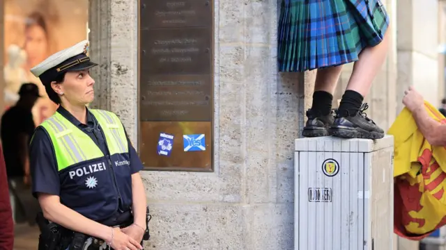 A female police officer looks towards the legs of a Scotland fan wearing a kilt ahead of UEFA EURO 2024