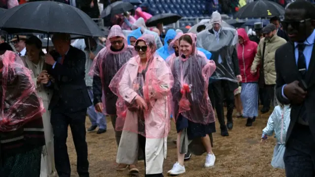 People wearing ponchos and umbrellas dodge the rain at Trooping the Colour