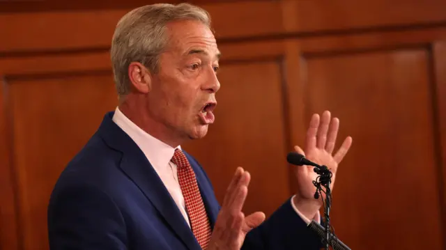 Nigel Farage gestures as he speaks into a microphone