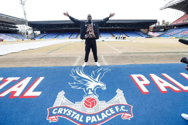 Richard Riakpore stands on the edge of the pitch at Selhurst Park