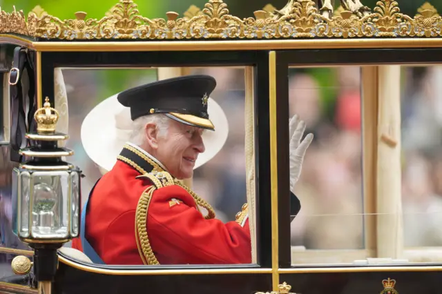 King Charles smiles and waves at the crowd