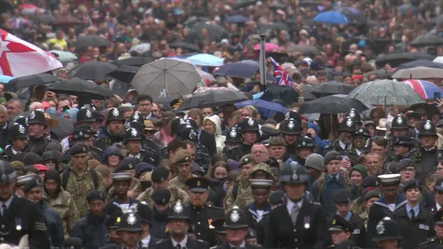 People wearing ponchos and umbrellas dodge the rain at Trooping the Colour