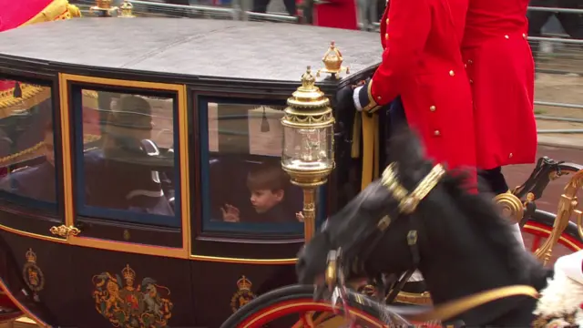 Prince Louis waves to the crowd from a carriage.