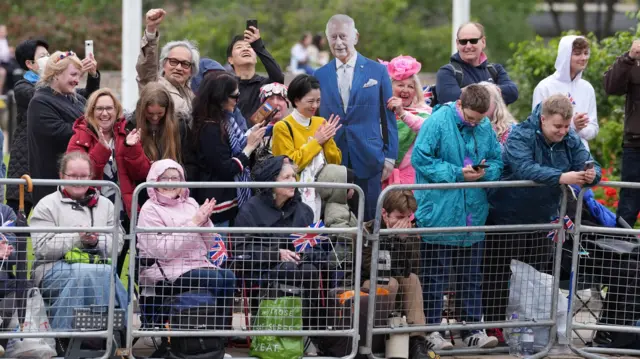 Royal fans pictured behind a barrier prepared with England flags and a cut-out of King Charles