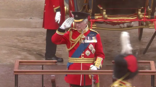 The King salutes in the pouring rain.