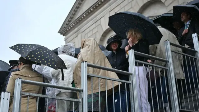 People wearing ponchos and umbrellas dodge the rain at Trooping the Colour