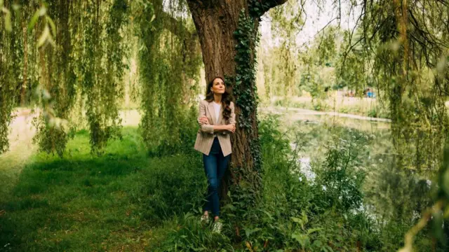 Princess of Wales stands in front of a tree.