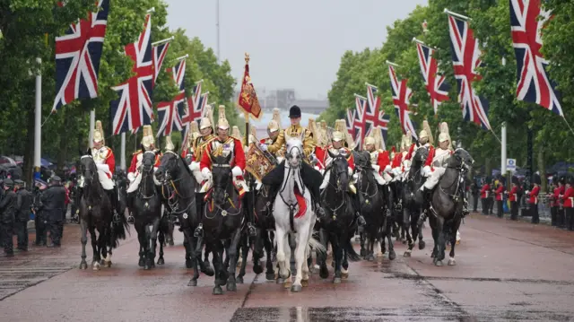 Members of the military on horseback progressing along the Mall