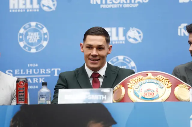 Chris Billam-Smith sits at a table for a news conference next to his WBO cruiserweight title