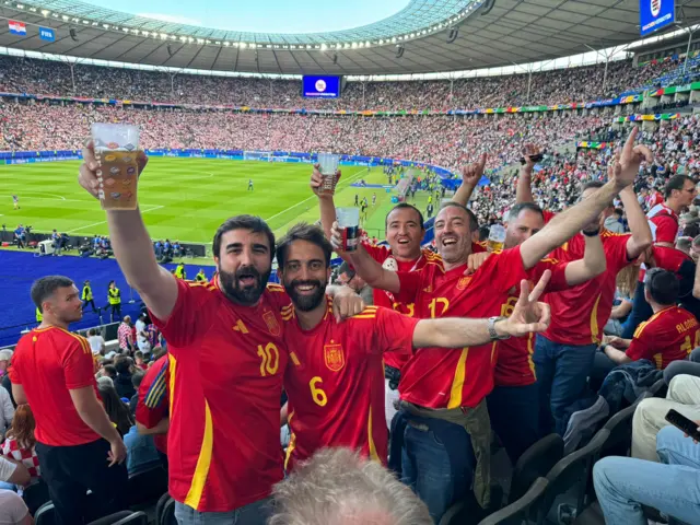 A group of Spanish fans pose and cheer for their team