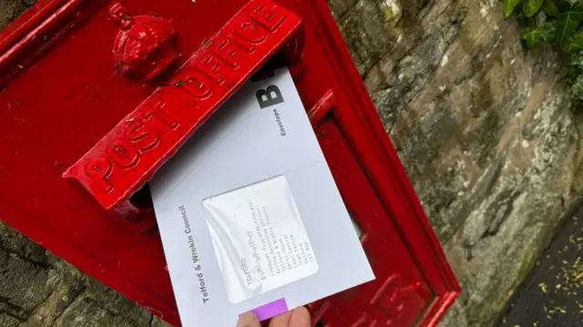 Postal vote being placed in a letter box