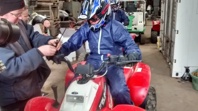 Willie Rennie wearing a boiler suit and helmet riding a quad bike