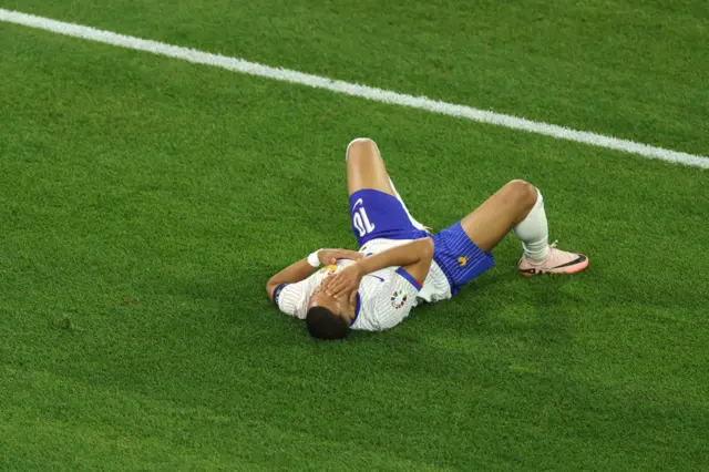 Kylian Mbappe holding his face on the grass