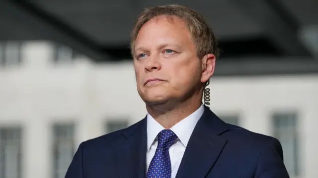 Grant Shapps wearing a suit and tie while looking off into the distance