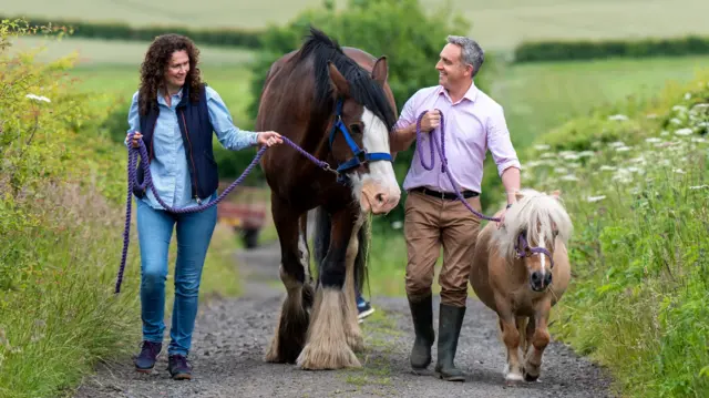 Scottish Lib Dem leader Alex Cole-Hamilton and deputy leader Wendy Chamberlain walk with horses at a farm