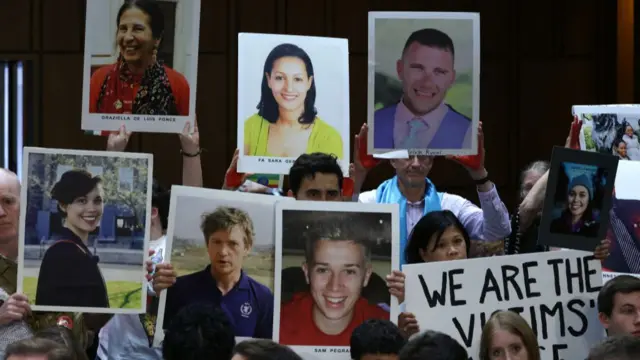 Family members hold up signs in a Boeing hearing