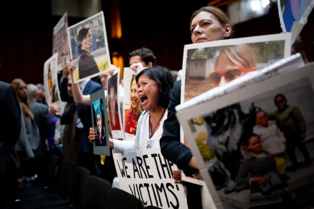 Clariss Moore of Toronto, Canada, holds a photograph of her daughter Danielle Moore and stands with other family members of those killed in the Ethiopian Airlines Flight 302 and Lion Air Flight 610 as she becomes emotional while screaming at Boeing CEO Dave Calhoun as he departs following a Senate Homeland Security and Governmental Affairs Investigations Subcommittee hearing on Boeing's broken safety culture.