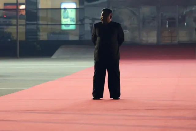 Kim Jong Un standing on the red carpet on the tarmac