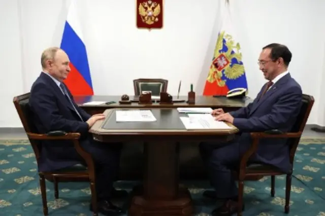 Russia's Vladimir Putin sits at a table across from Aisen Nikolayev