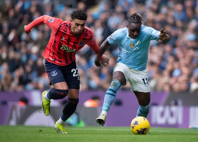 Jeremy Doku of Manchester City is challenged by Ben Godfrey of Everton