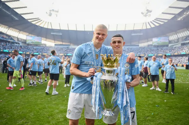 Erling Haaland and Phil Foden hold the Premier League trophy