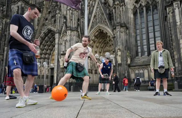 Scotland fans play football in front of Cologne Cathedral.