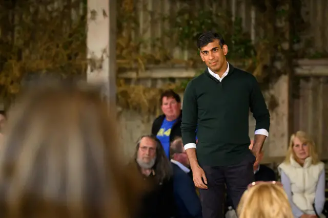 British Prime Minister Rishi Sunak speaks to farmers as he campaigns on a farm near Barnstaple in North Devon