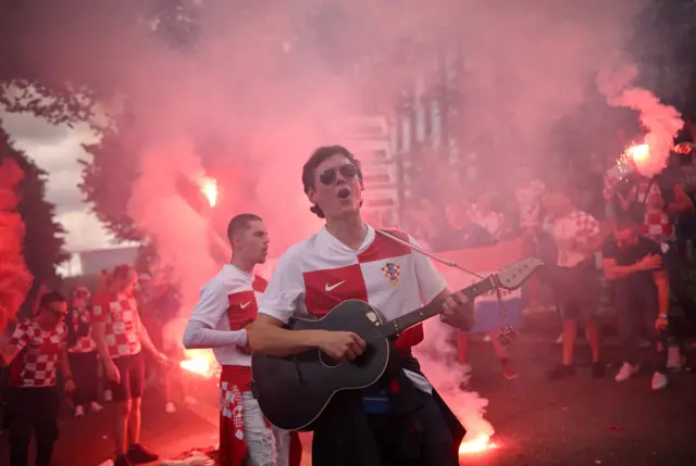 A croatia fan sings and plays the guitar among cleebrations