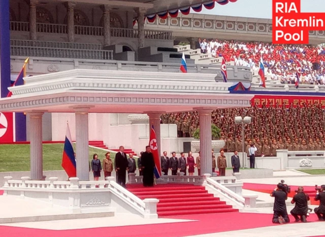 Putin and Kim stand at a welcome ceremony