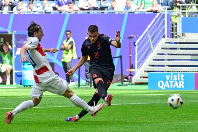 Asllani shoots at goal while Modric tries to cover