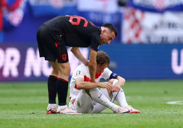 Modric sinks to the floor as he is comiserated by an Albania player