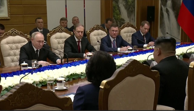 The two leaders and their senior ministers sit at a long table exchanging commitments