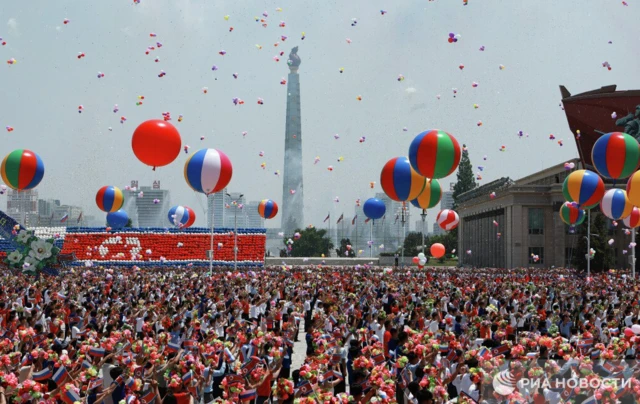 The gathered crowds holding flowers and balloons and cheering