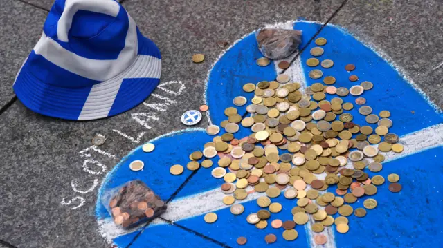 Coins left in a Saltire chalk drawing in Cologne