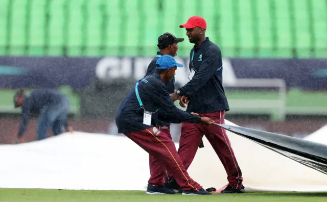 Groundstaff bring the covers on during the West Indies v Papua New Guinea game