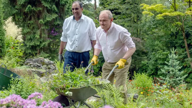 Ed Davey pushes a wheelbarrow full of plants