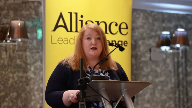 Alliance leader Naomi Long speaks from a podium