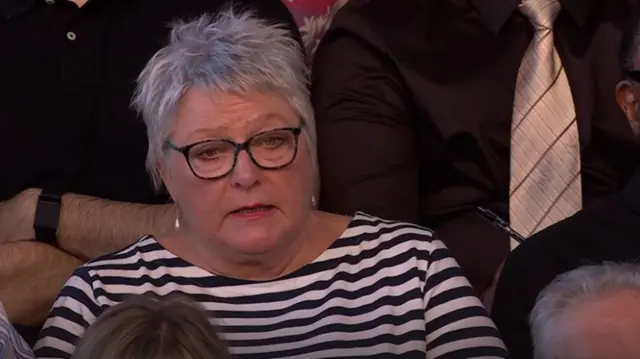 Linda asking a question, wearing stripy stop and glasses