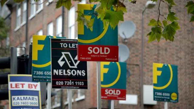 Real estate signs are seen in front of a building.