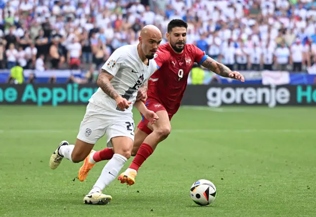 Drkusic of Slovenia runs with the ball whilst under pressure from Aleksandar Mitrovic