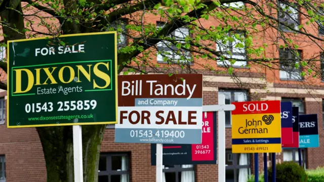 A long line of different for sale signs outside block of flats