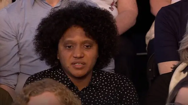 Woman wearing a black and white spotted top in the audience